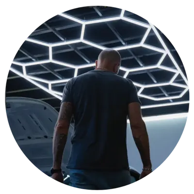 Custom hexagonal LED ceiling grid lighting matrix by OZ Lighting, installed at the Folien-Xtreme vehicle wrapping and car detailing workshop in Villach, Austria, providing shadow-free precision illumination.